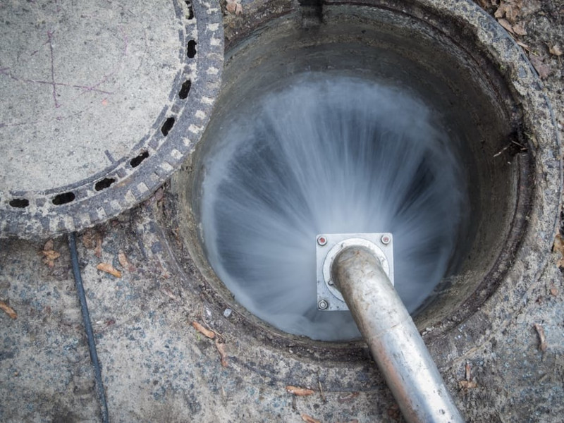 Professional hydro jetting equipment cleaning a drain line